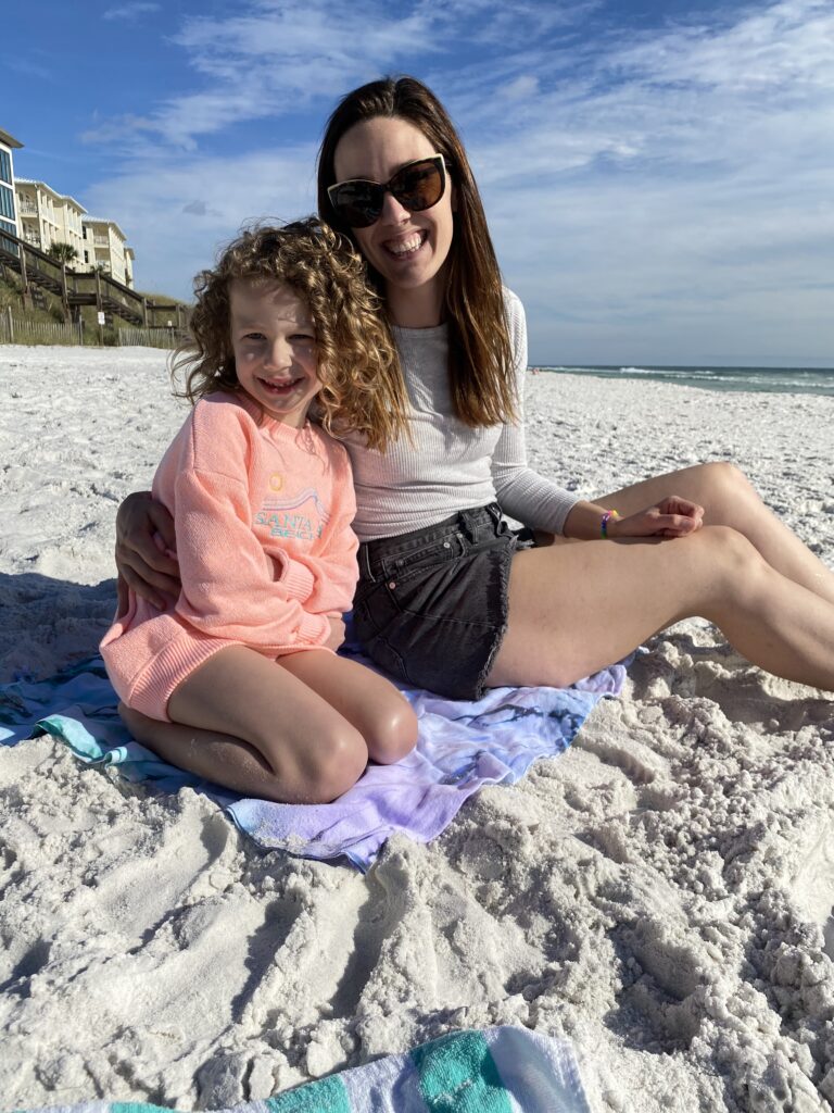 Mom and daughter sitting on the beach